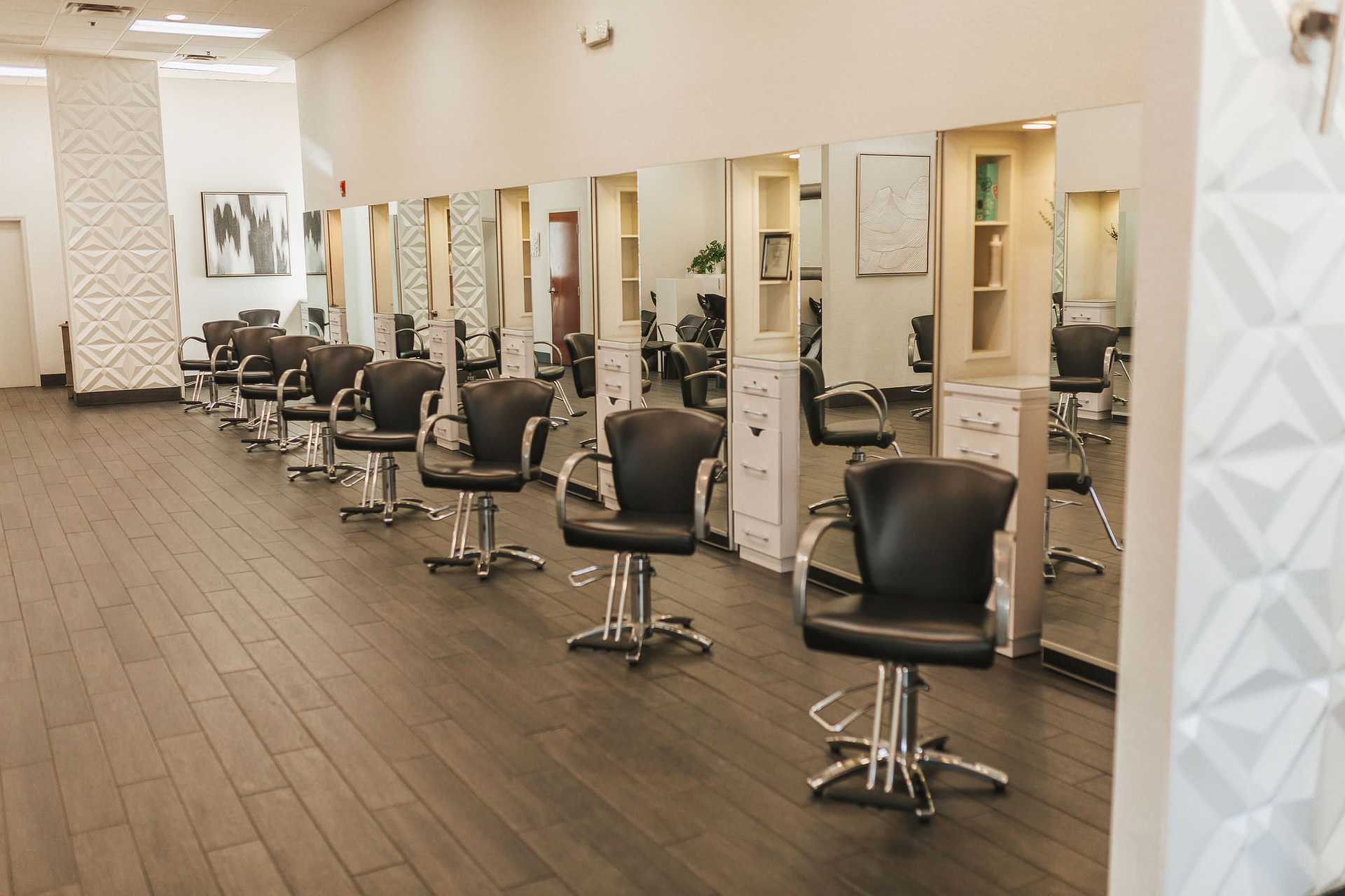 Modern salon with black chairs, mirrors, and wooden flooring, ready for clients.