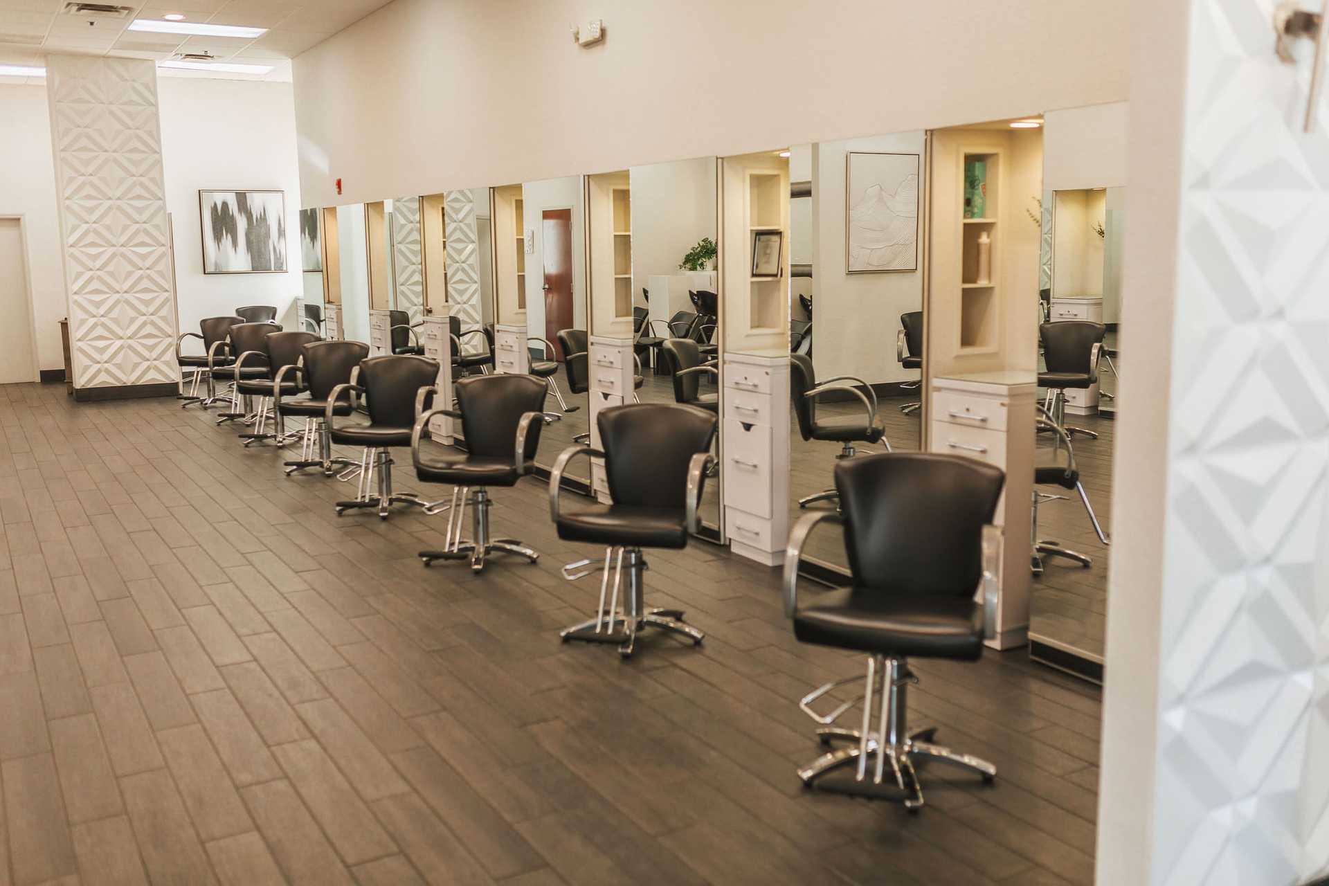 Modern salon with black chairs, mirrors, and wooden flooring, ready for clients.